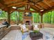 A beautiful outdoor living space featuring a brick fireplace, comfortable seating, and a ceiling fan for relaxation at 7329 Kennington Ct, Charlotte, NC 28270