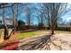 Backyard view featuring mature trees, green lawn, concrete patio, and wooden fence, with neighboring houses in the background at 102 Brewster Ct, Mooresville, NC 28115