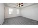 Bright bedroom featuring new carpet, a ceiling fan, and two windows providing natural light at 102 Brewster Ct, Mooresville, NC 28115