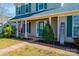 Inviting front porch with an American flag, lush landscaping, and a bright green front door at 102 Brewster Ct, Mooresville, NC 28115