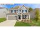 Charming two-story home features a manicured front yard, gray siding, and an attached two-car garage at 157 Saidin Ln, Troutman, NC 28166