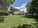 Spacious backyard featuring lush green grass, tiered landscaping, and a view of the home's rear exterior at 3600 Carmel Rd, Charlotte, NC 28226