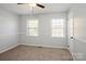 Cozy bedroom with neutral carpet, light-grey walls, ceiling fan, and two bright double-hung windows at 6322 Old Pineville Rd # E, Charlotte, NC 28217