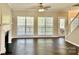 Bright living room with hardwood floors, fireplace, large windows, and a ceiling fan at 10550 Worsley Ln, Charlotte, NC 28269