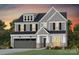 Two-story home featuring gray siding, black shutters, stone accents, and a two-car garage at 1056 Kinship Dr # 113, Lancaster, SC 29720