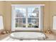 Bright bathroom featuring a soaking tub with a large window view of the property's well-manicured outdoor space at 119 Era St, Troutman, NC 28166