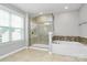 Bathroom showcasing glass-enclosed shower and separate soaking tub with decorative tile surround at 14125 Derby Farm Ln, Charlotte, NC 28278