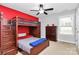 Bedroom with bunkbeds, ceiling fan, neutral carpet, and red accent wall at 14125 Derby Farm Ln, Charlotte, NC 28278