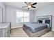 Bright bedroom with ceiling fan and neutral tones with view of the residential area through the window at 14125 Derby Farm Ln, Charlotte, NC 28278