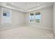 Bright bedroom featuring neutral walls, carpet, tray ceiling, and double windows showcasing outdoor views at 1615 Shoals Ave # 158, Belmont, NC 28012