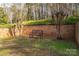 The peaceful backyard displays a brick wall, a simple bench and mature trees, perfect for relaxation at 246 Jerry Crump Rd, Lincolnton, NC 28092