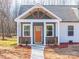 A close-up of a home's inviting front porch with a wooden railing, orange door, and meticulously maintained landscaping at 2853 W Zion Church Rd, Shelby, NC 28150