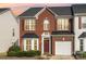 Charming brick two-story townhome with red shutters, black roof and an attached white one-car garage at 3822 Carl Parmer Dr, Harrisburg, NC 28075