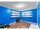 Bedroom featuring blue walls, wood-look floors, two windows, and striped curtains at 41 Fleetwood Sw Dr # 44, Concord, NC 28027