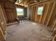 Unfinished room with exposed wood framing, two windows, and plywood flooring at 4688 Glen Stripe Dr # Cal0069, Indian Trail, NC 28079