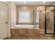 Luxurious bathroom featuring a soaking tub, separate glass-enclosed shower, and a tile window at 472 Barber Loop, Mooresville, NC 28117