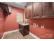 Laundry room with wooden cabinets, granite sink, window, and tiled floors at 472 Barber Loop, Mooresville, NC 28117