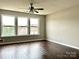 This bedroom has three windows with outside views, a ceiling fan, and wood flooring at 7306 Fox Point Dr, Charlotte, NC 28269