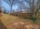 Fenced backyard with grass and leaves, surrounded by mature trees at 1007 Little John Trl, Kannapolis, NC 28081