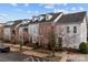 A street view displays townhomes with a mix of brick and white siding under a bright cloudy sky at 11406 Potters Row, Cornelius, NC 28031