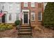 Charming townhouse entryway with brick steps, American flag, and decorative wreath on the black door at 11406 Potters Row, Cornelius, NC 28031