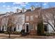 Attractive townhouses with a mix of brick and white siding, American flags, and blooming trees at 11406 Potters Row, Cornelius, NC 28031