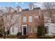 A classic brick and siding townhouse with dormer windows, American flags, and blooming trees at 11406 Potters Row, Cornelius, NC 28031