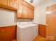 Laundry room with light wood cabinets, a washer and dryer set, wood paneled walls and tile flooring at 1200 Berkshire Dr, Kannapolis, NC 28081