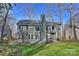 Back exterior featuring a spacious yard with lush grass, patio, and beautiful mature trees at 12724 Cliffcreek Dr, Huntersville, NC 28078