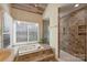 Bright bathroom features a soaking tub under a window and a tiled walk-in shower at 12724 Cliffcreek Dr, Huntersville, NC 28078