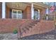 Inviting front porch with brick steps, wrought iron railing, columns, and an American flag on display at 12724 Cliffcreek Dr, Huntersville, NC 28078