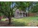 Backyard shot of a shed with covered porch and seating, surrounded by greenery and wooden fence at 1921 Kenilworth Ave, Charlotte, NC 28203