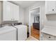 Functional laundry room with white appliances, cabinets, and a glimpse of the living room at 3725 Plumgrove Ct, Charlotte, NC 28210