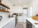 Practical kitchen with white cabinets, open shelving, and a stacked washer/dryer unit at 4310 Randolph Rd, Charlotte, NC 28211