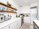 Efficient kitchen with white cabinets, open wood shelves, and a stacked washer/dryer at 4310 Randolph Rd, Charlotte, NC 28211