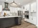 Open kitchen boasts stainless steel appliances, white cabinets, a gray island, and wood floors at 7206 Sumters Camp Trl, Fort Mill, SC 29707
