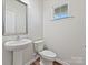 Cozy half bathroom featuring pedestal sink, toilet, and natural light at 9021 Ramsford Ct, Mint Hill, NC 28227