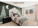 The bedroom has decorative tree and moon wall art and a plaid bedspread with black dresser, and natural light at 11016 Tyler Brook Ln # Oak0036, Mint Hill, NC 28227