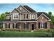 Inviting two-story home with a mix of stone and siding and a covered front porch at 11020 Tyler Brook Ln # Oak0035, Mint Hill, NC 28227