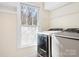 Well-lit laundry room featuring modern washer and dryer units and a window at 11121 Timber Hill Ct, Charlotte, NC 28226