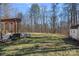 View of backyard from the deck with mature trees and an additional storage building at 15314 Logan Grove Rd, Charlotte, NC 28227