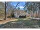 View of a two-story home with a long driveway, a lawn, and mature trees at 15314 Logan Grove Rd, Charlotte, NC 28227