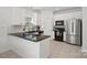 Well-lit kitchen with white cabinets, black countertops, stainless steel appliances, and subway tile backsplash at 15314 Logan Grove Rd, Charlotte, NC 28227