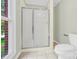 Neutral bathroom featuring a glass shower door, toilet, window, and beige tile floor at 2041 Jefferson Ave, Gastonia, NC 28056