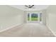 A large bedroom with carpeted floor, a ceiling fan, and a beautiful backyard view through the windows at 2041 Jefferson Ave, Gastonia, NC 28056