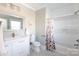 This bathroom has a white vanity, toilet, and shower/tub combo, as well as mosaic tile flooring and flower-print curtains at 2526 Fort St, Charlotte, NC 28205