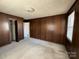 Bedroom featuring classic wood paneling, neutral carpet, and access to an adjacent room at 3412 1St Avenue Nw Cir, Hickory, NC 28601
