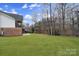 Large grassy backyard and a view of the home's exterior, set against a backdrop of trees and a bright blue sky at 411 Belo Ct, Fort Mill, SC 29715