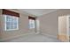 Neutral bedroom featuring two windows with blinds, plush carpeting, and an entrance to another room at 411 Belo Ct, Fort Mill, SC 29715