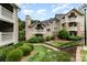 Multi-story condo with a well-maintained lawn, shrubbery, and black iron stair railing at 5011 Sharon Rd # B, Charlotte, NC 28210